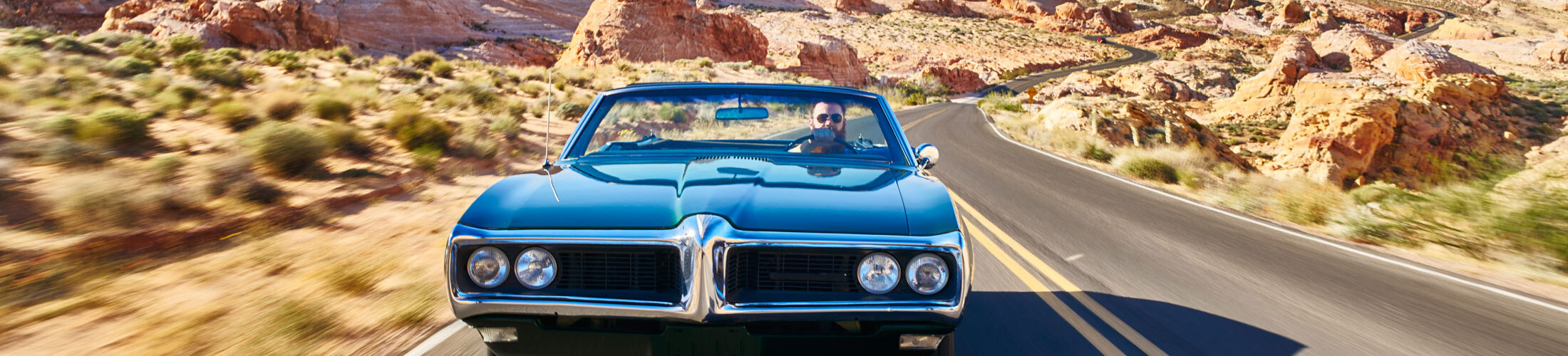 Man driving car desert road