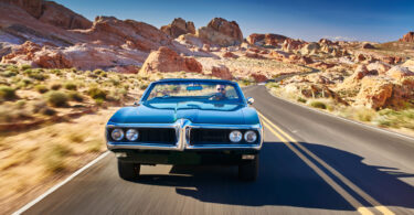 Man driving car desert road