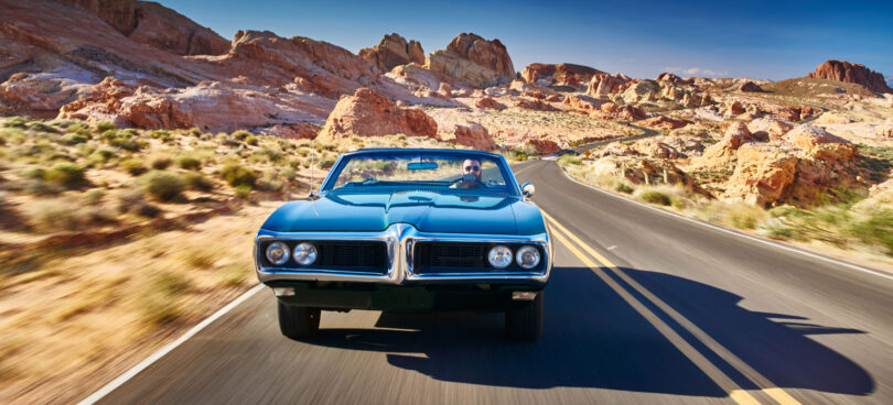 Man driving car desert road